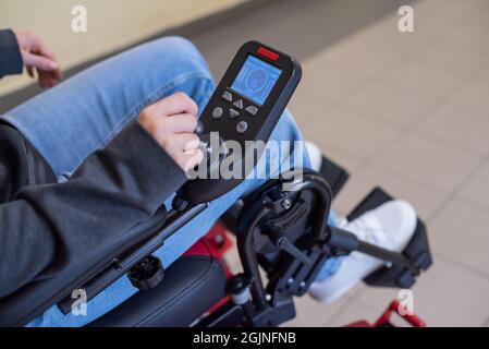 Primer plano de una mano femenina en el mango de control de una silla de ruedas eléctrica Foto de stock