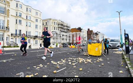 Brighton Reino Unido 12th de septiembre de 2021 - Los corredores toman líquidos  a bordo en una estación de bebidas ya que miles de corredores participan en  la maratón de Brighton hoy después de que la carrera de los últimos años  fue cancelada 