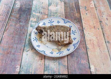 costillas marinadas con perejil y ajo asado en su jugo en un hermoso plato de cerámica en la parte superior de una mesa Foto de stock