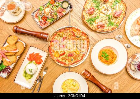 Pruebe el típico conjunto de la gastronomía italiana con las pizzas habituales, ensalada de burrata, espaguetis boloñese visto desde el cenit Foto de stock