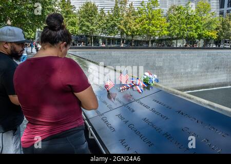 Nueva YORK, EE.UU., 21 de septiembre de 2021 - Las banderas y las flores estadounidenses se ven junto a los nombres de las víctimas del ataque terrorista en la Memoria Nacional del 11 de septiembre