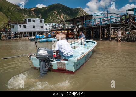 Un residente en un pequeño barco con motor externo se acerca a las casas de pilotes ('pang uk') en el río Tai O en Tai O, Isla Lantau, Hong Kong