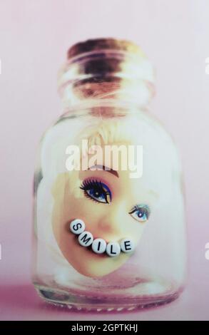 Una cabeza de Barbie atrapada en una botella con un corcho con la palabra 'milla'. Foto de stock