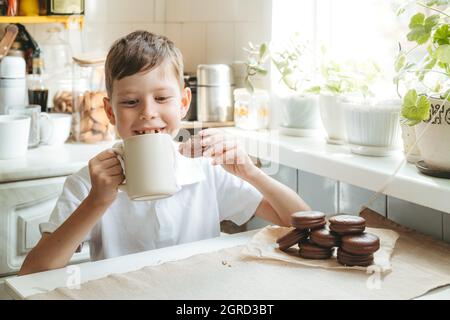 Niño que bebe leche de chocolate y que come galletas en casa Fotografía de  stock - Alamy