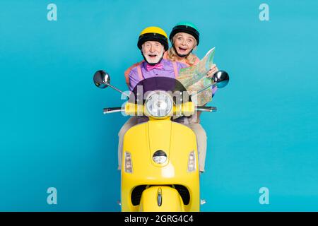 Foto de pareja casada de pelo gris montar en bicicleta mapa feliz hold viaje de vacaciones aislado en color azul pastel fondo Foto de stock