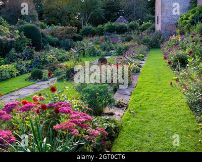 Chenies Manor Jardín hundido a finales de septiembre. Césped alrededor del estanque ornamental, vibrante fronteras dahlia bellamente abastecido. Foto de stock