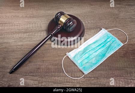 Gavel del juez de madera al lado De una máscara médica en la mesa. Covid 19 Concepto Ncov.