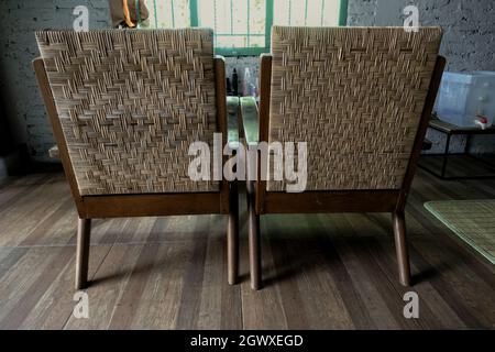 dos sillas de ratán y baldosas con motivos de madera en la habitación que da a la ventana Foto de stock