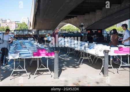 La gente que navega por los puestos en el Southbank Center Book Market, situado en Queens Walk bajo Waterloo Bridge, Londres, Inglaterra, Reino Unido Foto de stock