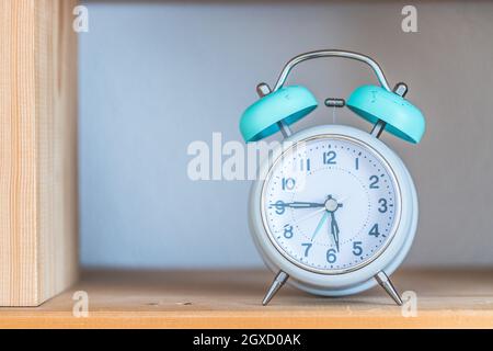 Reloj despertador blanco estilo retro en la estantería de madera Foto de stock