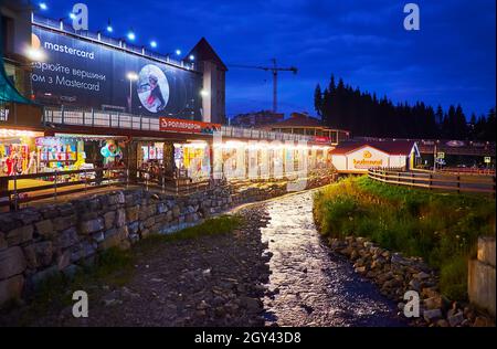 BUKOVEL, UCRANIA - 25 DE JULIO de 2021: Los pequeños puestos luminosos del mercado turístico en el estrecho arroyo de montaña, el 25 de julio en Bukovel Foto de stock