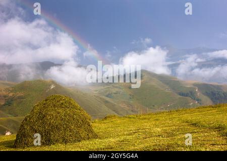 Hermoso paisaje de montaña con arco iris y pajar. Montañas de la República de Daguestán, Rusia. Foto de stock