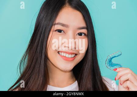 Retrato joven asiática hermosa mujer sonriendo sosteniendo retenedores de silicona ortodoncia para los dientes, dientes que retienen herramientas después de aparatos de sujeción extraíbles, Ortodont Foto de stock