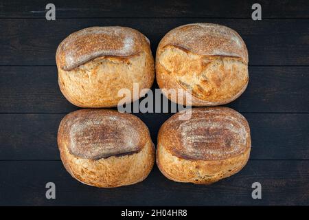 El pan artesanal de trigo se encuentra en la superficie de un color oscuro, fondo, vista superior.