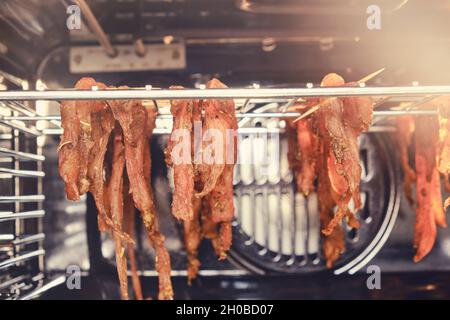 La carne de pollo se seca en la parrilla en el horno en la cocina de casa, cerca de arriba