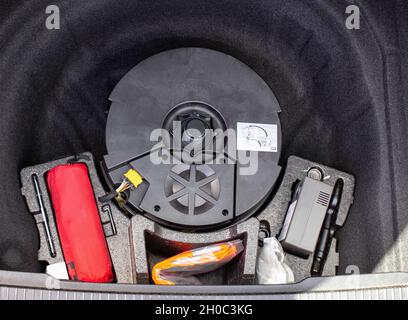 subwoofer original, kit de primeros auxilios y compresor para inflar ruedas en un nicho de maletero de coche, equipo