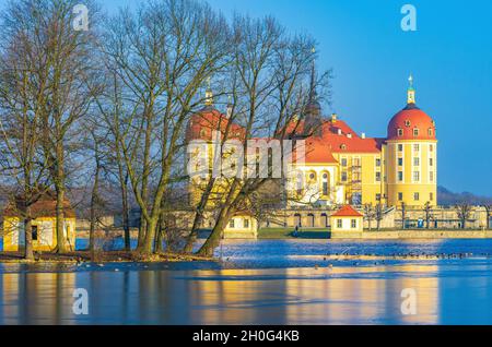 Moritzburg cerca de Dresden, Sajonia, Alemania: Wintry Moritzburg Palace detrás del grupo de árboles de un islote de pato situado en el estanque del palacio medio congelado. Foto de stock