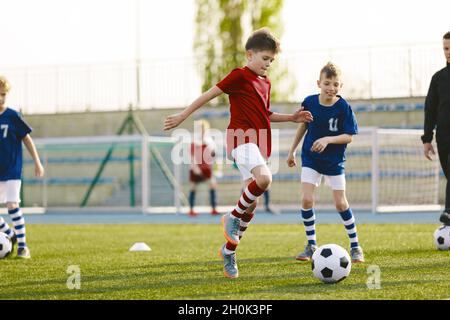 Atletas juveniles en camisas de fútbol rojas y azules. Dos chicos compiten por el balón. Educación deportiva. Jugadores de fútbol para niños Pateando el balón en la FIE de fútbol