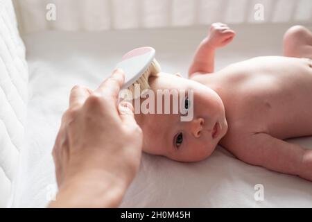 Cepillo para el cabello y cuidado del bebé. madre peinando el