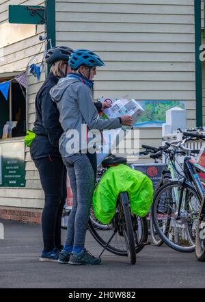 dos mujeres ciclistas leyendo mapa para encontrar direcciones en un paseo en bicicleta en la isla de wight reino unido. paseos, ciclismo vacaciones, ciclistas perdidos, lectura de mapa. Foto de stock