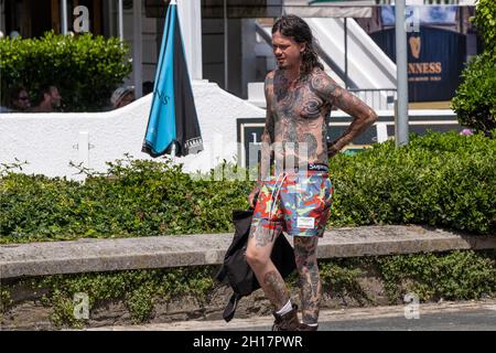 Un joven tatuado pesadamente con tatuajes de estilo japonés Irezumi caminando en un soleado centro de Newquay en Cornwall. Foto de stock
