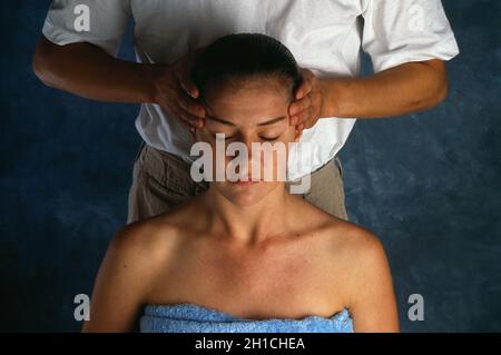 Fisioterapeuta masajeando la cabeza de una mujer joven. Foto de stock