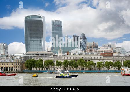 barco de policía en el río támesis con rascacielos de la ciudad de londres en el fondo Foto de stock