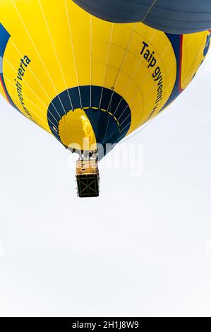 Vilnius, Lituania - 14 de septiembre de 2021: Un globo de aire caliente amarillo vibrante con un grupo de pasajeros se deshace al cielo en Vilnius, Lituania. Foto de stock