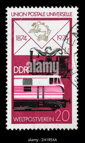Sello impreso en RDA muestra viejas locomotoras a vapor y diesel moderno, centenario de la UPU, circa 1974 Foto de stock