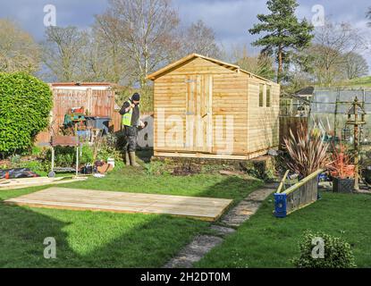 Trabajadores de Solid Sheds Ltd erigiendo un cobertizo de madera en un jardín doméstico, Stoke on Trent, Staffordshire, Inglaterra, Reino Unido. Foto número 6 en una serie de 8 Foto de stock