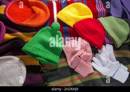 Los sombreros, bufandas y guantes de punto multicolor están dispuestos en el mostrador como decoración Foto de stock