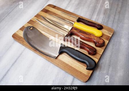 Juego de cuchillos de cocina y tabla de picar sobre un fondo marrón  Fotografía de stock - Alamy