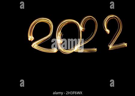Nuevo año 2022 próximo concepto foto. Pintura ligera luz amarilla dibujada 2022 sobre fondo negro. Feliz año nuevo. Fotografía de larga exposición.