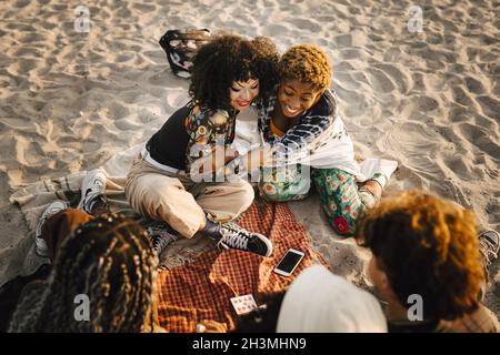 Chica adolescente sonriente abrazando a un amigo no binario en la playa