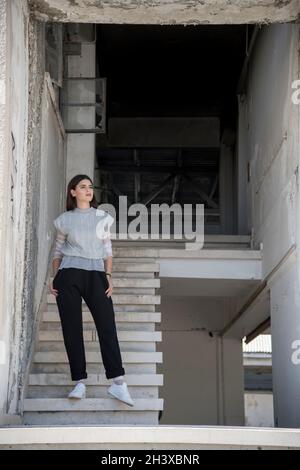 Mujer joven con camisa gris y pantal n negro de pie en las