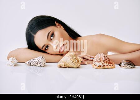 Hermosa mujer afroamericana con diferentes conchas sobre fondo blanco