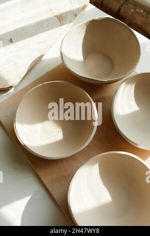 Imagen de fondo mínima de placas cerámicas crudas en estudio de cerámica iluminado por la luz del sol, espacio de copia