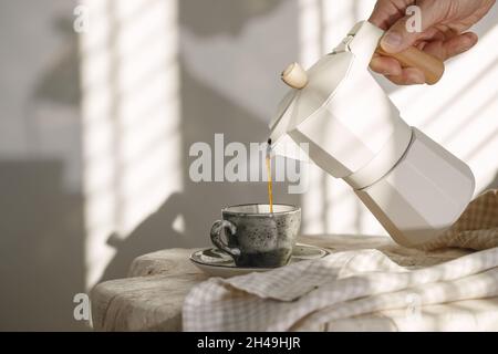 Verter el café de una cafetera eléctrica italiana, rodada en low key.  Vierta el café negro macho de manos de la italiana moka brewer Fotografía  de stock - Alamy