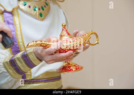 Un hombre en la ropa de Aladdin . Una persona sostiene en su mano lámpara  de oro realista de Aladdin . vieja en sus manos la lámpara mágica de Aladdin.  Sosteniendo un