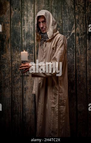 Hombre alto con vestido largo sacerdote con pared vieja de madera Foto de stock