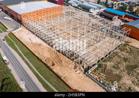 construcción de un nuevo almacén en el área residencial. construcción de un marco de acero. vista aérea desde el drone. Foto de stock