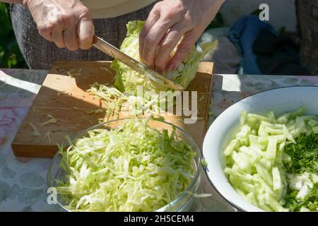 Mujer tiras de repollo ensalada de col cortador manual en la tabla