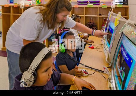 Un maestro de pre-kindergarten ayuda a los estudiantes a jugar un juego de matemáticas en la computadora, 18 de mayo de 2012, en Columbus, Mississippi. Foto de stock