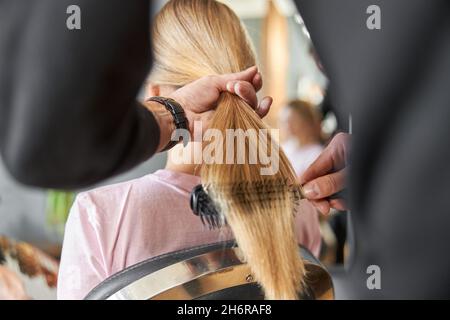 Pofessional peluquería está peinando un pelo de hermosa mujer blanca rubia en el salón moderno Foto de stock