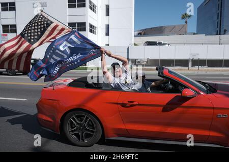 Los Ángeles, CA, EE.UU. 8th de agosto de 2020. Un hombre ondea una bandera estadounidense y una bandera pro Trump desde un convertible en una concentración semanal en Los Ángeles. Crédito: Imágenes de aumento/Alamy Foto de stock