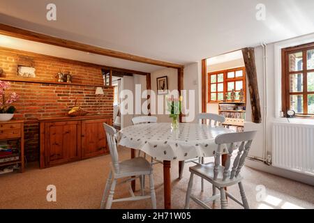 Whepstead, Suffolk, Inglaterra - 2 2020 de junio: Zona de comedor tradicional en el interior del hogar con pared de ladrillo visto con una pequeña mesa y sillas Foto de stock