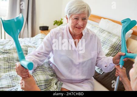 Retrato de una mujer mayor sonriente con muletas en el gimnasio del  hospital
