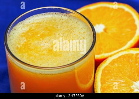 Bonito zumo de naranja recién exprimido en mitades de vidrio y naranja Foto de stock