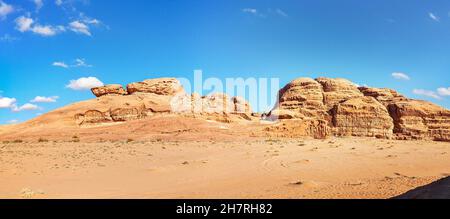 Macizos rocosos en el desierto de arena roja, cielo azul brillante en el fondo - paisaje típico en Wadi Rum, Jordania Foto de stock