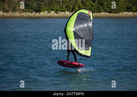 Persona windsurf deslizándose en el río Adur en Shoreham viajando a velocidad en el avión antes de girar a barlovento. Foto de stock
